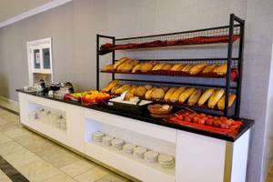 Frühstücksbuffet im Club Wasa Holiday Village mit Brot, Obst und Tomaten.