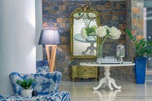Lobby des Arina Beach Resorts mit Steinwand, Spiegel, Tisch, Blumen und Lampen.