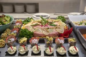 Buffet mit Vorspeisen im Vantaris Luxury Beach Resort Hotel, inklusive Salat, Fisch und kleinen Gerichten in Gläsern.