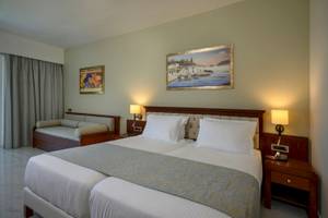 Doppelbett-Zimmer im Vantaris Palace Hotel mit gerahmten Gemälden an der Wand.