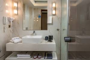 Badezimmer im Vantaris Palace Hotel mit Waschbecken, Handtüchern und Toilettenartikeln.