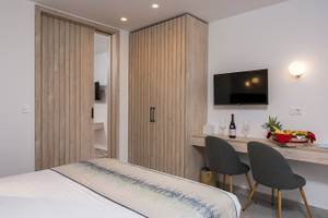 Innenansicht eines Zimmers im Vantaris Palace Hotel mit Bett, Schreibtisch und Fernseher.