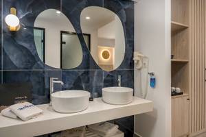 Badezimmer im Vantaris Palace mit zwei Waschbecken, Spiegeln und blauer Wandgestaltung.