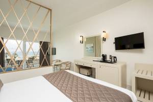 Hotelzimmer mit Meerblick im Vantaris Palace mit einem großen Bett, einem Schreibtisch und einem Fernseher an der Wand.