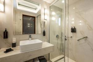 Badezimmer im Vantaris Palace Hotel mit weißer Marmorwand und Dusche