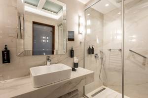 Badezimmer im Vantaris Palace mit Marmorfliesen, Dusche und Waschbecken.