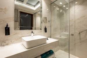 Das Badezimmer im Vantaris Palace mit weißem Waschbecken und Spiegeln.