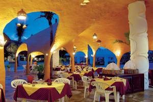 Restaurant im Southern Palms Beach Resort mit gelben Wänden und roten Tischdecken.