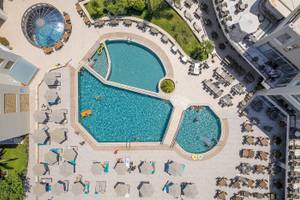 Luftaufnahme des Vantaris Palace mit Swimmingpools, Sonnenliegen und Schirmen.