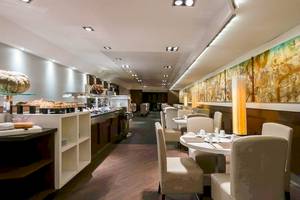 Frühstücksraum im Colonial Barcelona Hotel mit Tischen, Stühlen und Buffet.