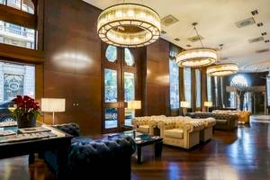 Empfangsbereich des Colonial Barcelona Hotels mit Sofas, Lampen und Holzböden.