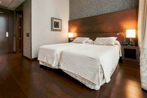 Schlafzimmer im Colonial Barcelona Hotel mit zwei Betten, Nachttischen und Lampen.