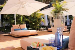 Gartenlounge-Bereich im Jardin Tecina Hotel mit einem Bett unter einem Schirm und einem Tablett mit Essen und Getränken.