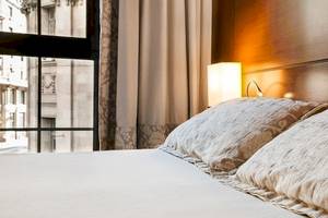 Bett im Colonial Barcelona Hotel mit Kissen und Fenster mit Stadtblick