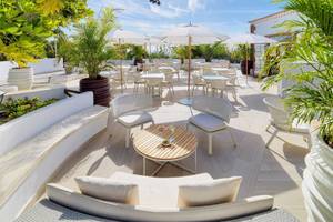 Garten Terrasse des Hotels Jardin Tecina mit weißen Tischen und Stühlen, Sonnenschirmen und Pflanzen.