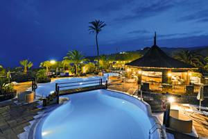 Ein abendlicher Blick auf den Pool des Jardin Tecina Hotels mit beleuchteter Bar und umgebenden Palmen.