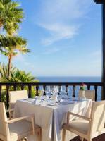 Gartentisch mit Meerblick im Hotel Jardin Tecina, serviert mit Wein und Blumen.