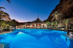 Außenpool des Jardin Tecina Hotels bei Abendbeleuchtung mit Blick auf die Bar und die Liegen