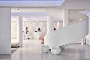 Innenbereich des Myconian Ambassador Hotels mit moderner weißer Architektur und Wendeltreppe.