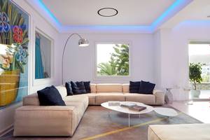 Wohnzimmer im Myconian Ambassador Relais & Chateaux Hotel mit Couch, Couchtisch und Lampe.